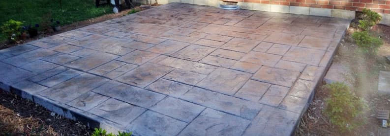 Completed stamped concrete patio with large flagstone pattern and color hardener finish