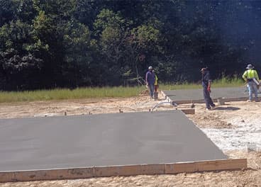 Concrete equipment pad freshly poured and leveled with forms still in place at a Tennessee job site