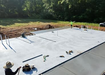 Large concrete slab pad finished and curing with crew wrapping up work in Middle Tennessee