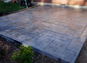 Completed stamped concrete patio with flagstone pattern next to a brick home in Middle Tennessee