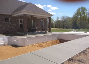 Concrete sidewalk poured alongside a new foundation wall at a brick home in Tennessee