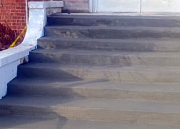 Freshly poured concrete steps with broom finish at a commercial building entrance